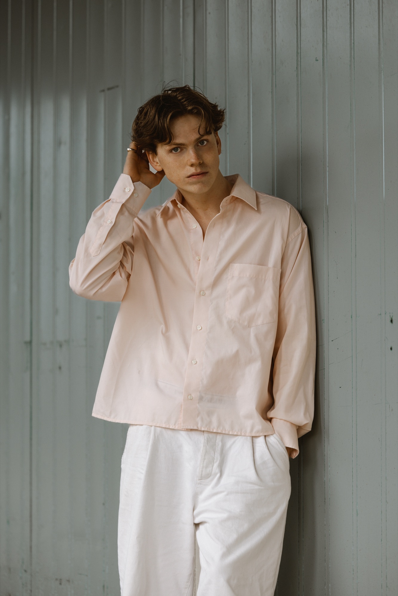 Senne against a pastel backdrop, hand at his ear